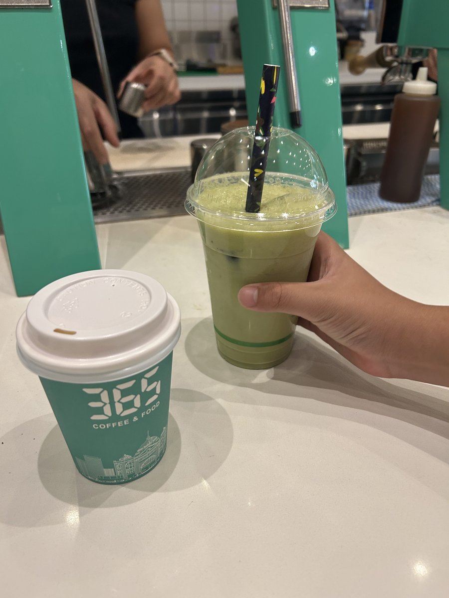 365 Coffee branded cup and iced matcha latte held in hand