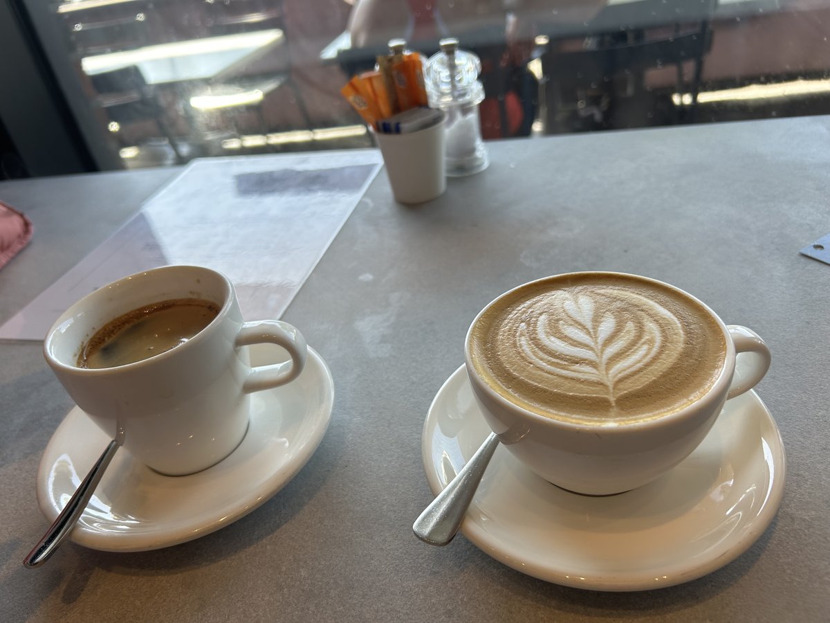 Espresso and a latte with leaf art on a window-side table at Au79