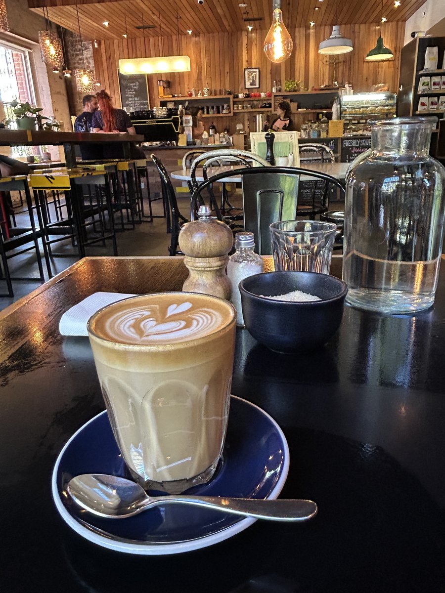 Latte with heart latte art on a table inside Black Gold's timber-lined interior