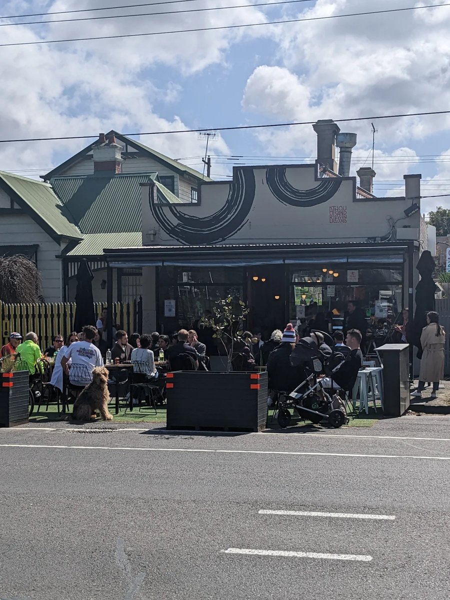 A Thousand Blessing storefront with circular logo mural and busy outdoor seating