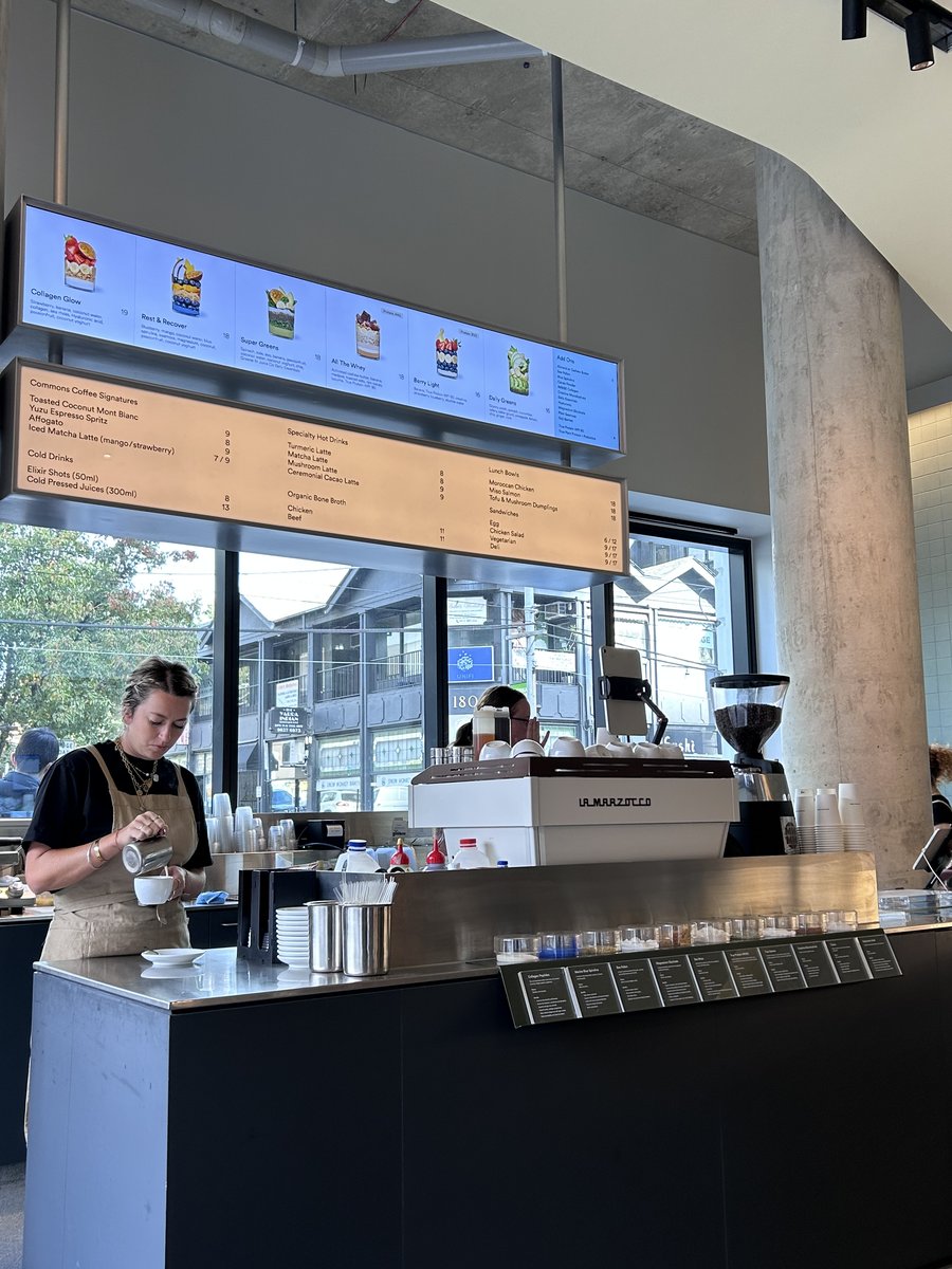 Barista at the counter at The Commons with menu boards overhead