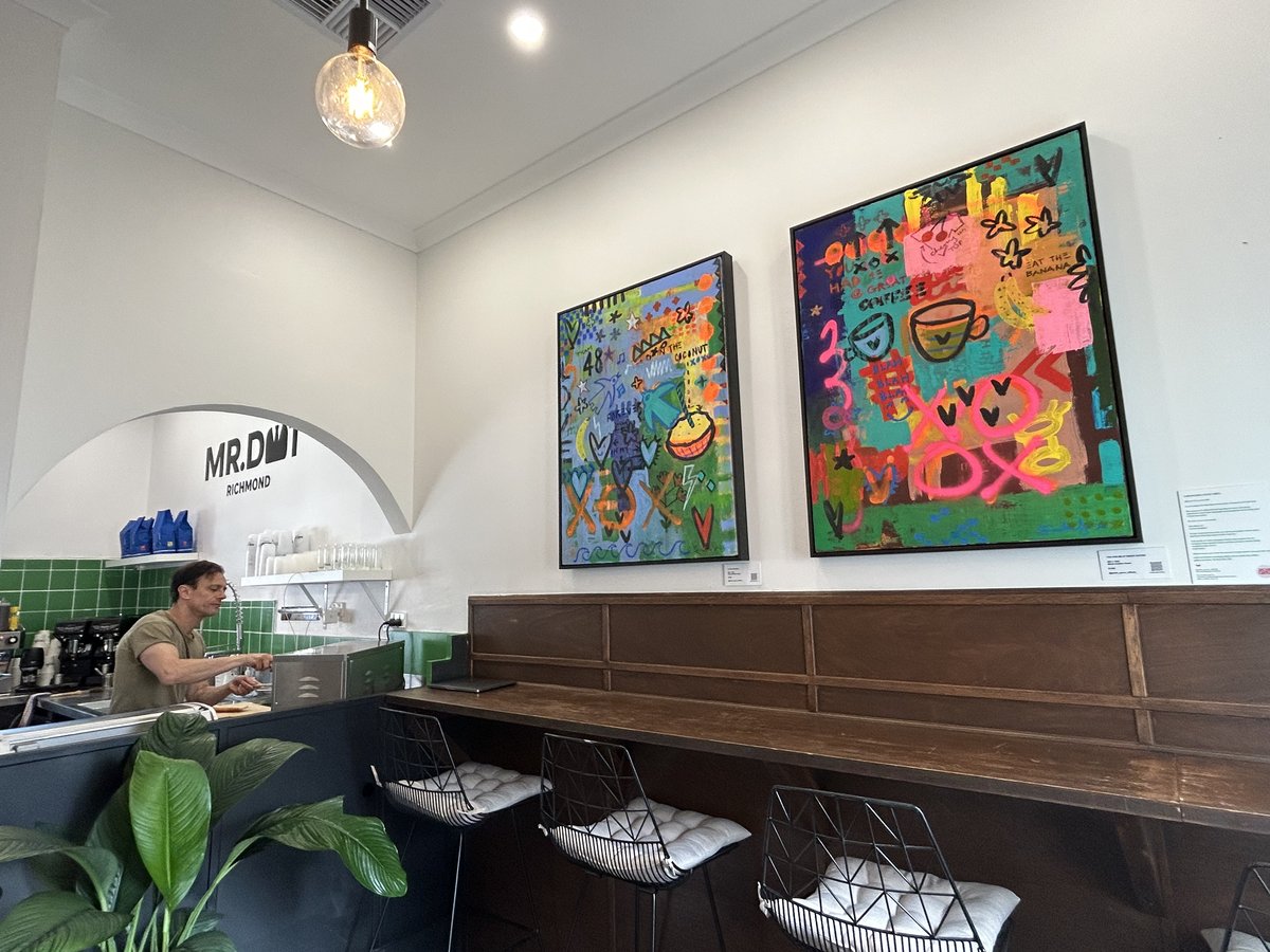 Barista at work beneath large colourful artworks at Mr. Dot Richmond