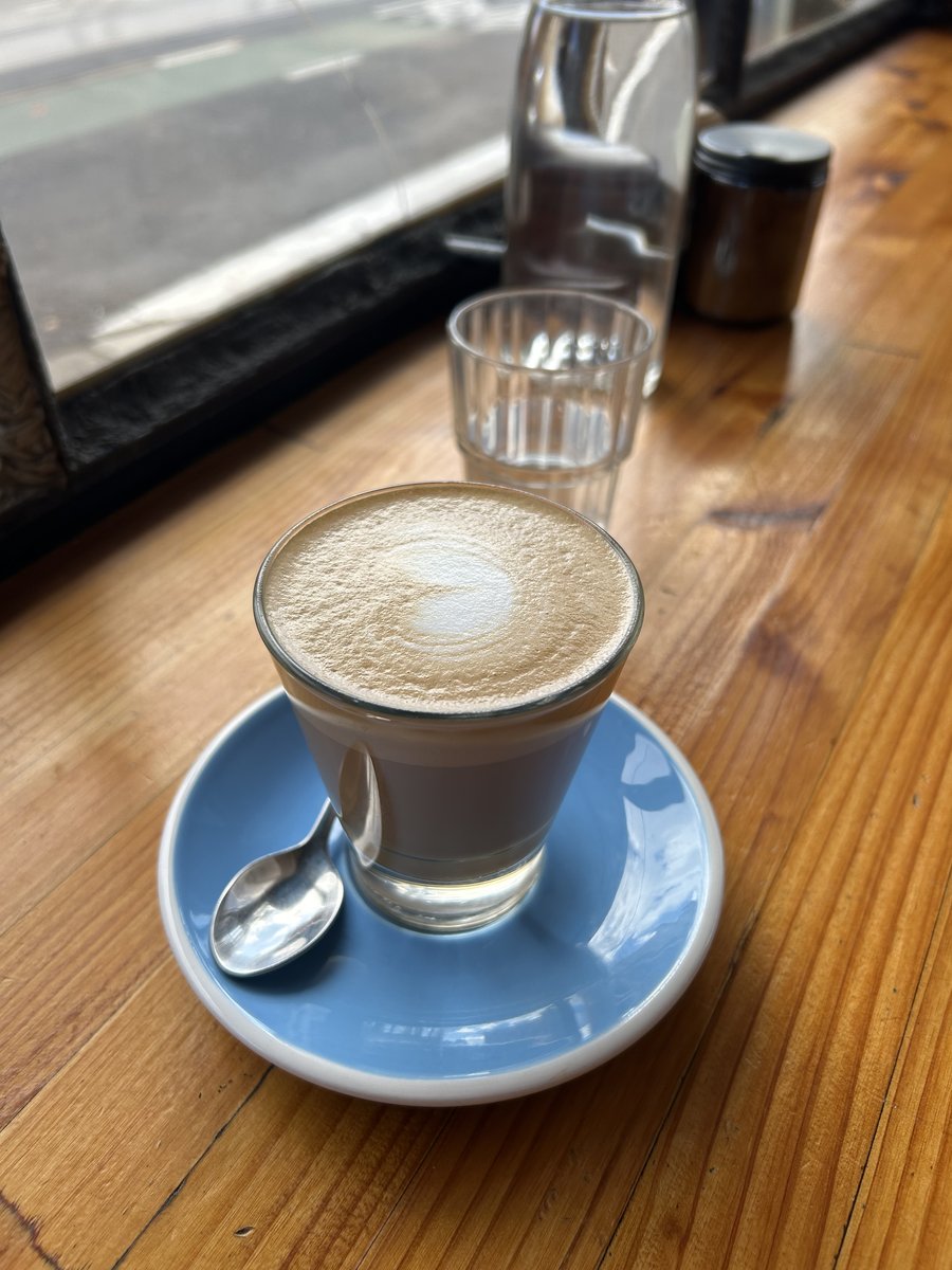 Latte glass on a blue saucer by the window at Pillar of Salt