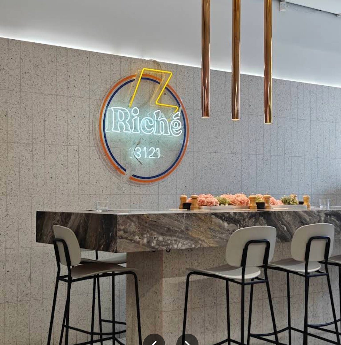 Riche neon sign above a marble communal table
