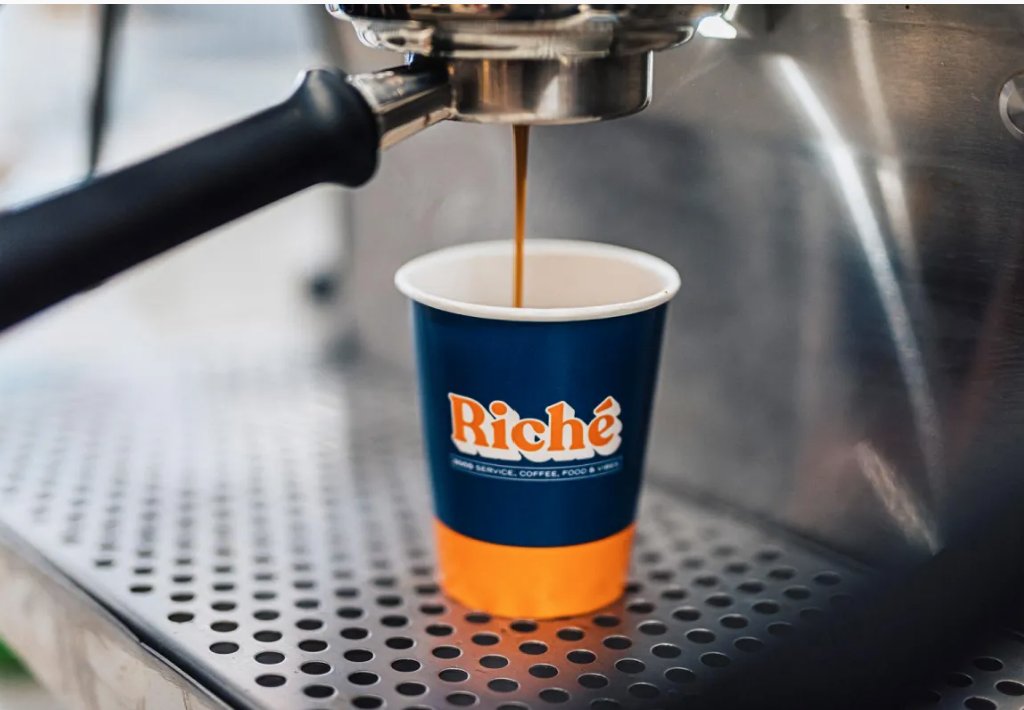Espresso pouring into a branded Riche cup